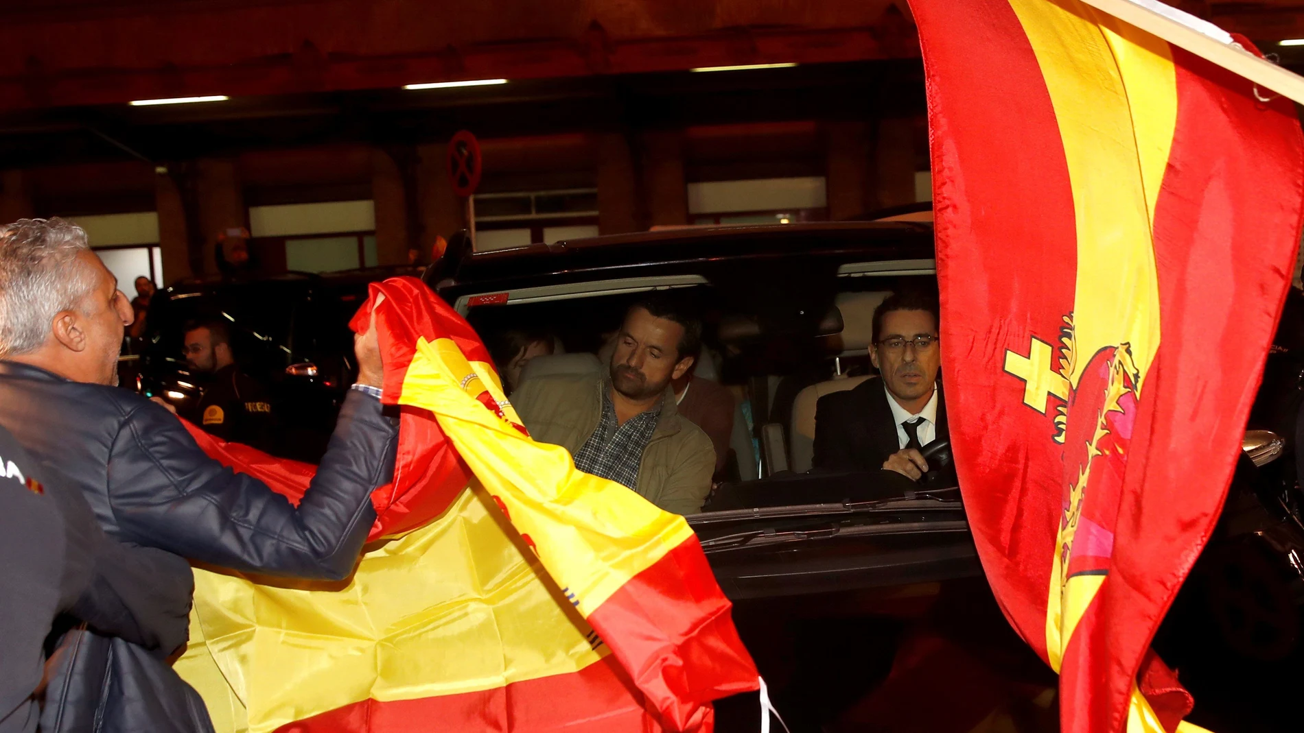Un grupo de personas con banderas españolas rodean el coche de los miembros de la mesa del Parlament