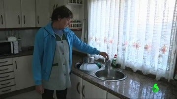 Una vecina de Faramontaos muestra el agua sucia que sale del grifo