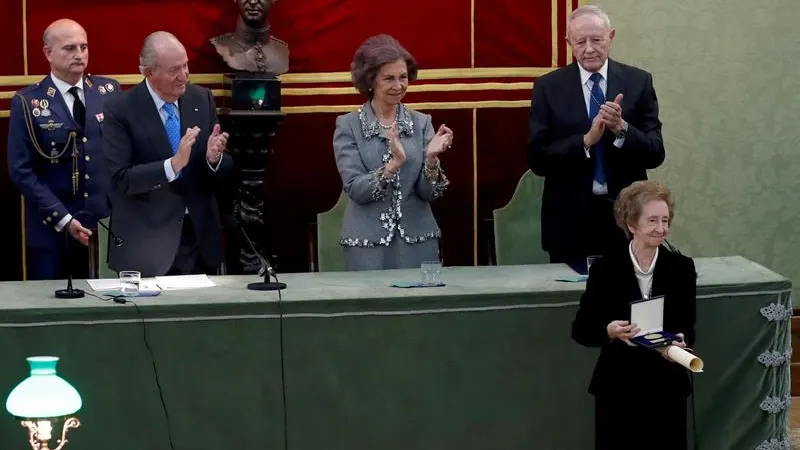 Margarita Salas enseñando el premio José Echegaray a los medios gráficos ante la tenta mirada de los Reyes eméritos