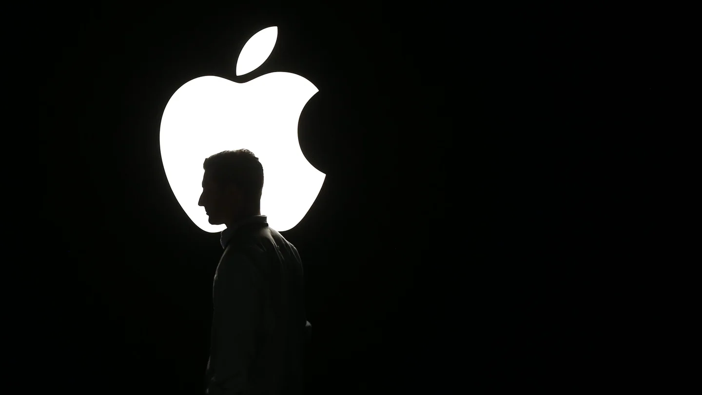 La silueta de un hombre se ve frente al logo de Apple La silueta de un hombre se ve frente al logo de Apple