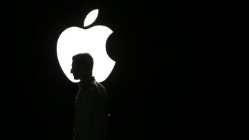 La silueta de un hombre se ve frente al logo de Apple