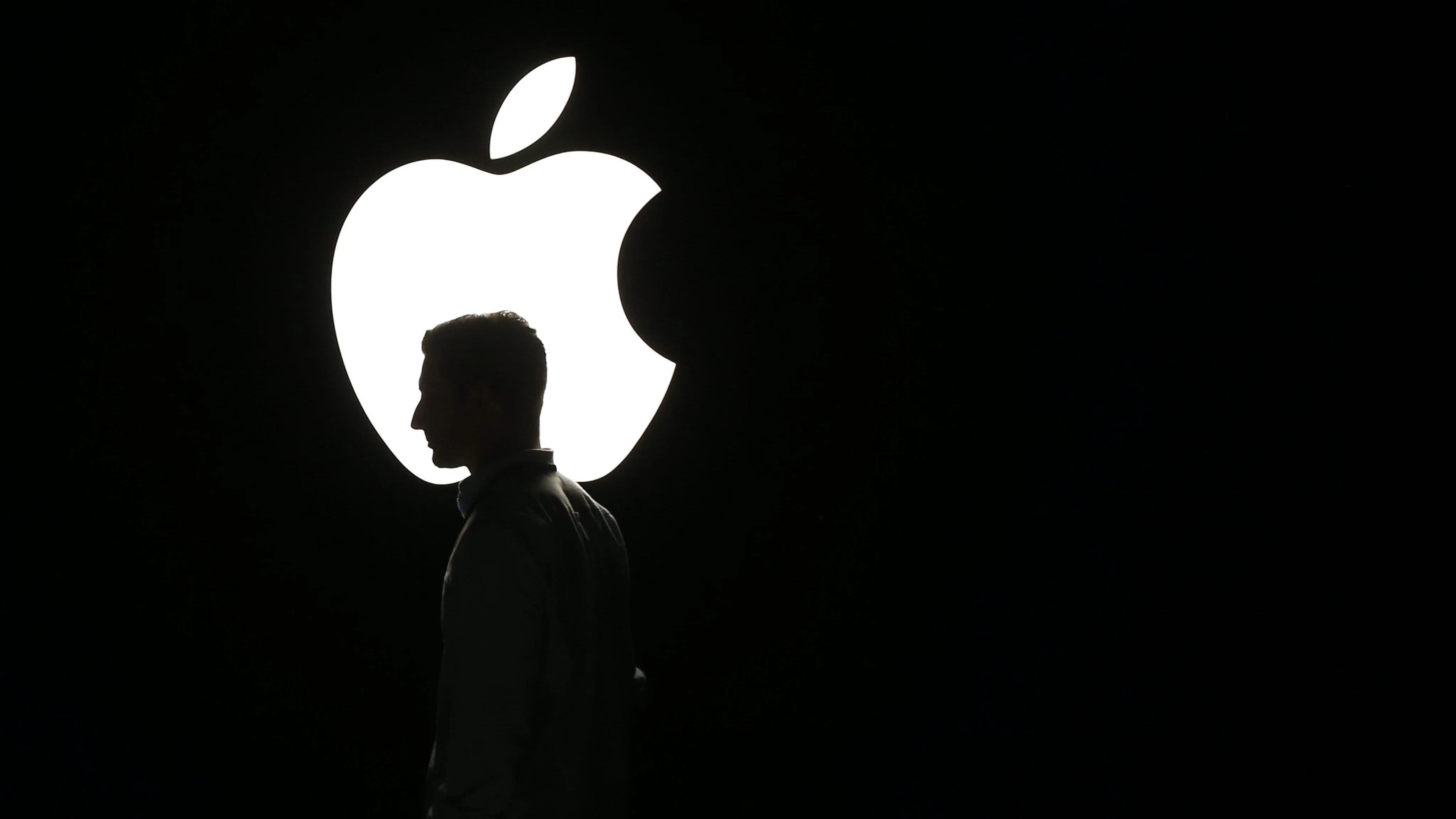 La silueta de un hombre se ve frente al logo de Apple