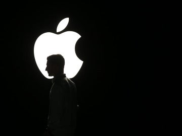 La silueta de un hombre se ve frente al logo de Apple La silueta de un hombre se ve frente al logo de Apple