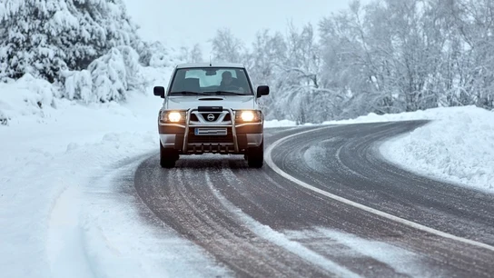 Un todoterreno circulando por una carretera nevada Un todoterreno circulando por una carretera nevada