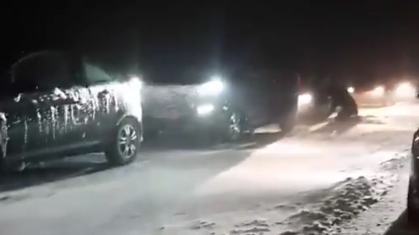 Veh&iacute;culos detenidos en una carretera nevada
