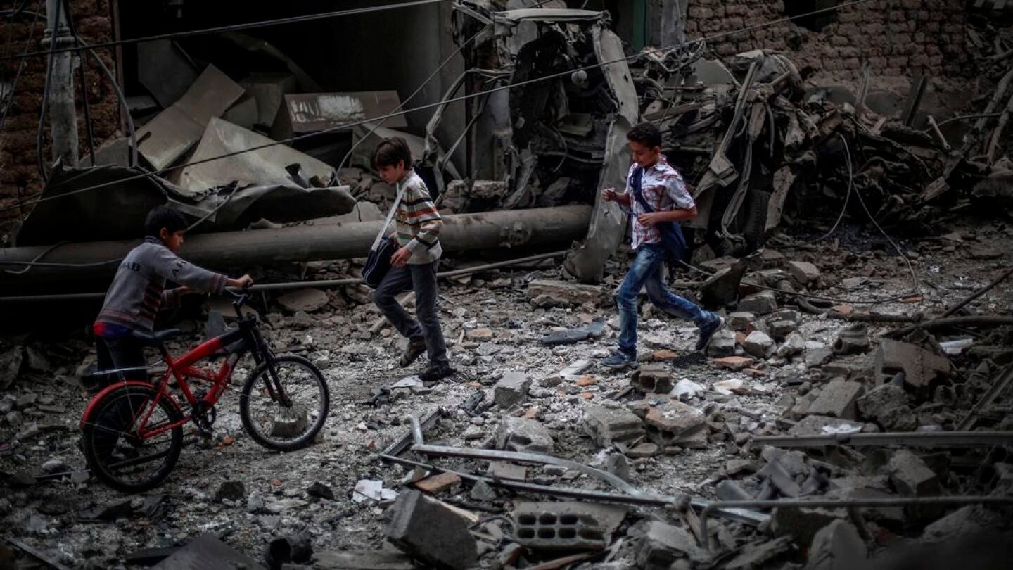 Ni&ntilde;os sirios observan los da&ntilde;os ocasionados tras un bombardeo a las afueras de Damasco