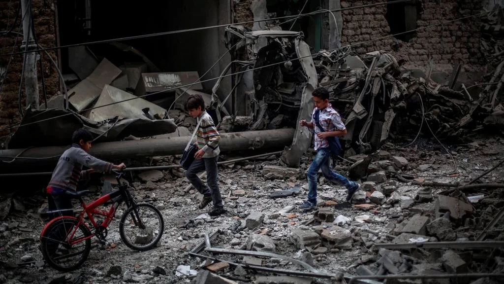 Niños sirios observan los daños ocasionados tras un bombardeo a las afueras de Damasco Niños sirios observan los daños ocasionados tras un bombardeo a las afueras de Damasco