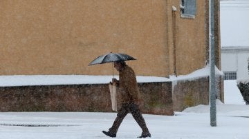 Un hombre camina bajo la nieve en la localidad salmantina de Guijuelo