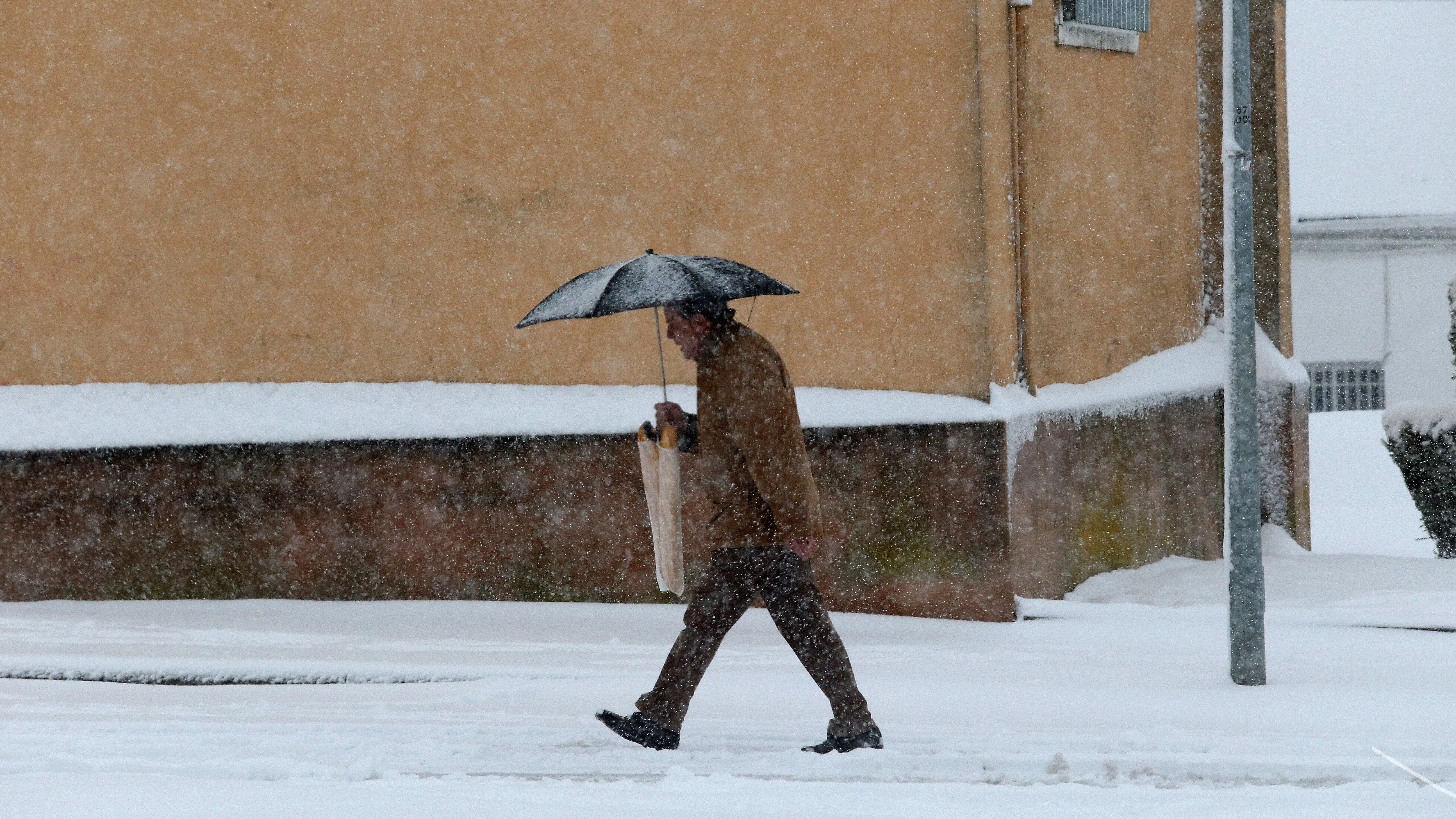 Un hombre camina bajo la nieve en la localidad salmantina de Guijuelo