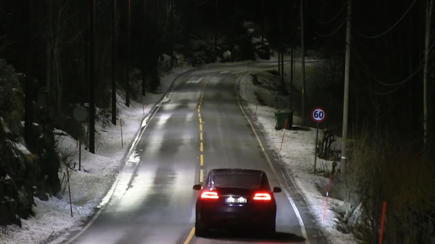 Los coches circulan por la carretera bajo la luz de las farolas inteligentes Los coches circulan por la carretera bajo la luz de las farolas inteligentes