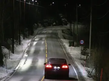 Los coches circulan por la carretera bajo la luz de las farolas inteligentes Los coches circulan por la carretera bajo la luz de las farolas inteligentes