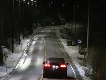Los coches circulan por la carretera bajo la luz de las farolas inteligentes Los coches circulan por la carretera bajo la luz de las farolas inteligentes