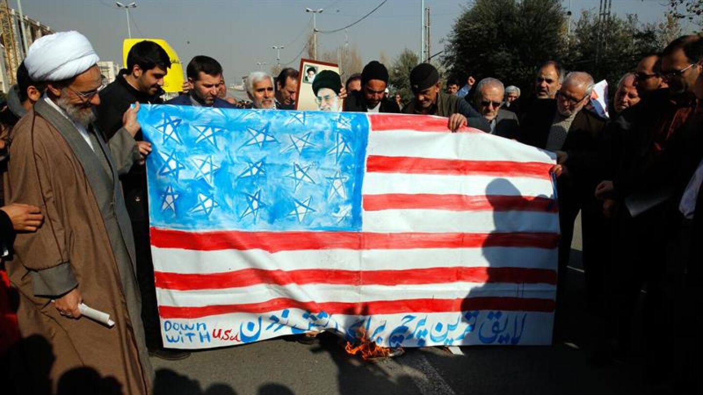 Manifestantes iran&iacute;es con una bandera de EEUU