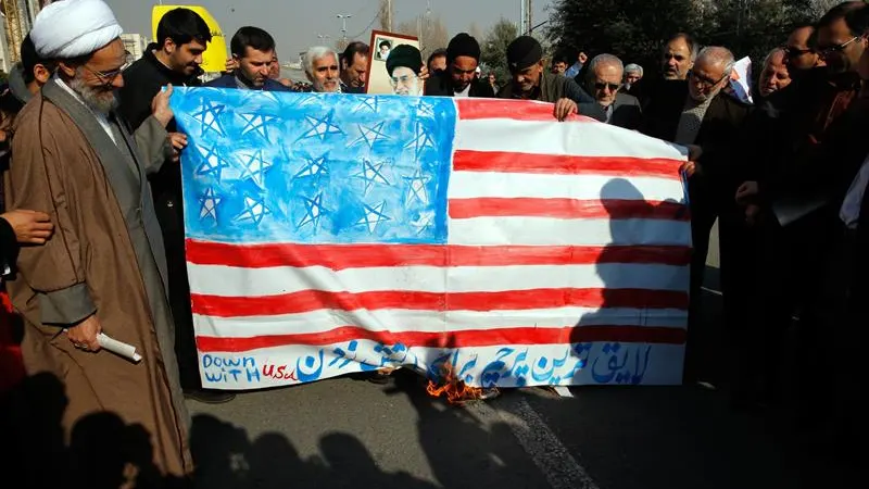 Manifestantes iraníes con una bandera de EEUU