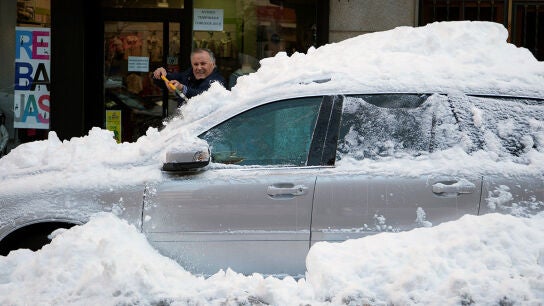 Un hombre retira la capa de nieve de un coche
