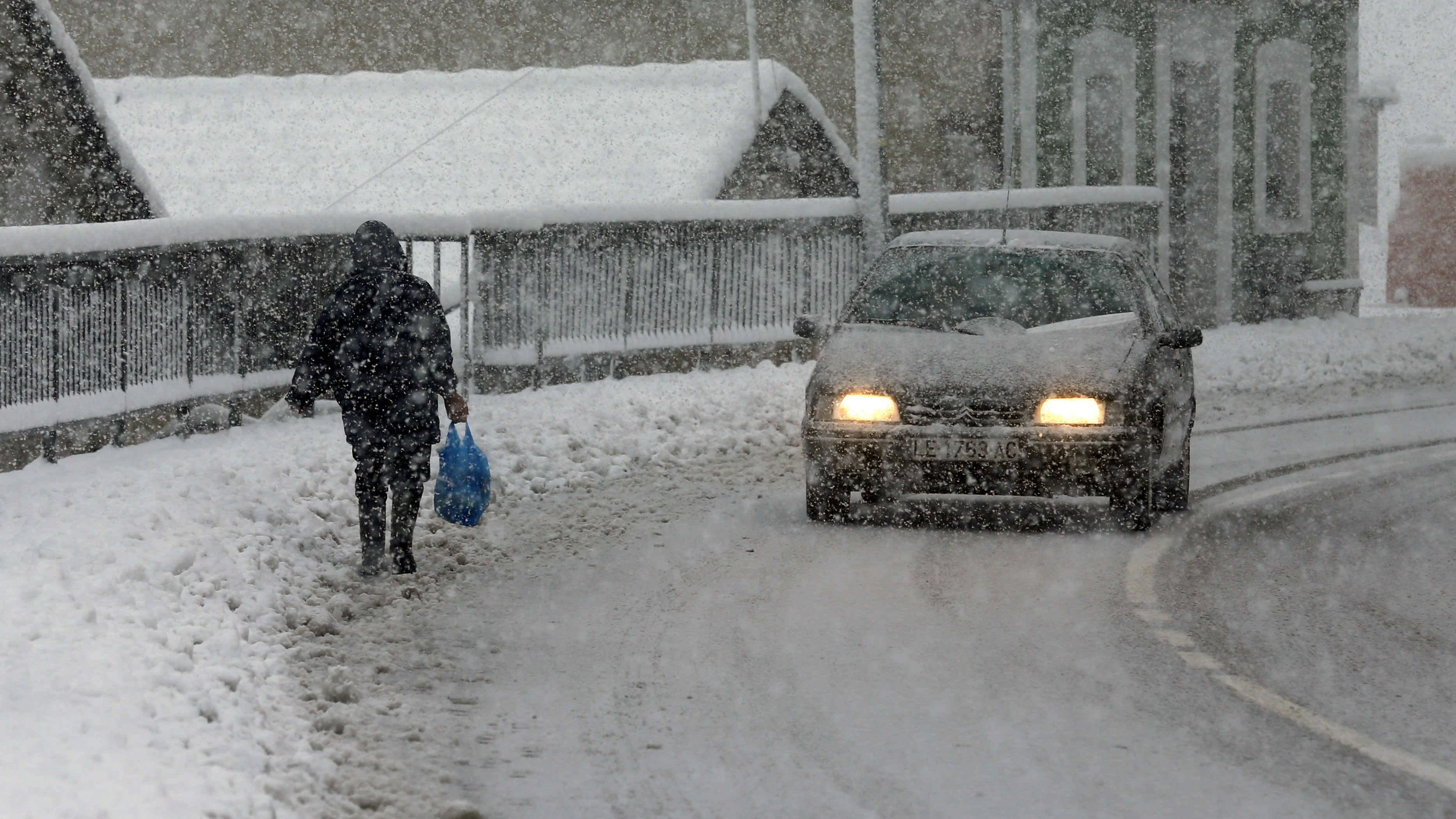 Una vecina del pueblo de Pajares camina entre la nieve