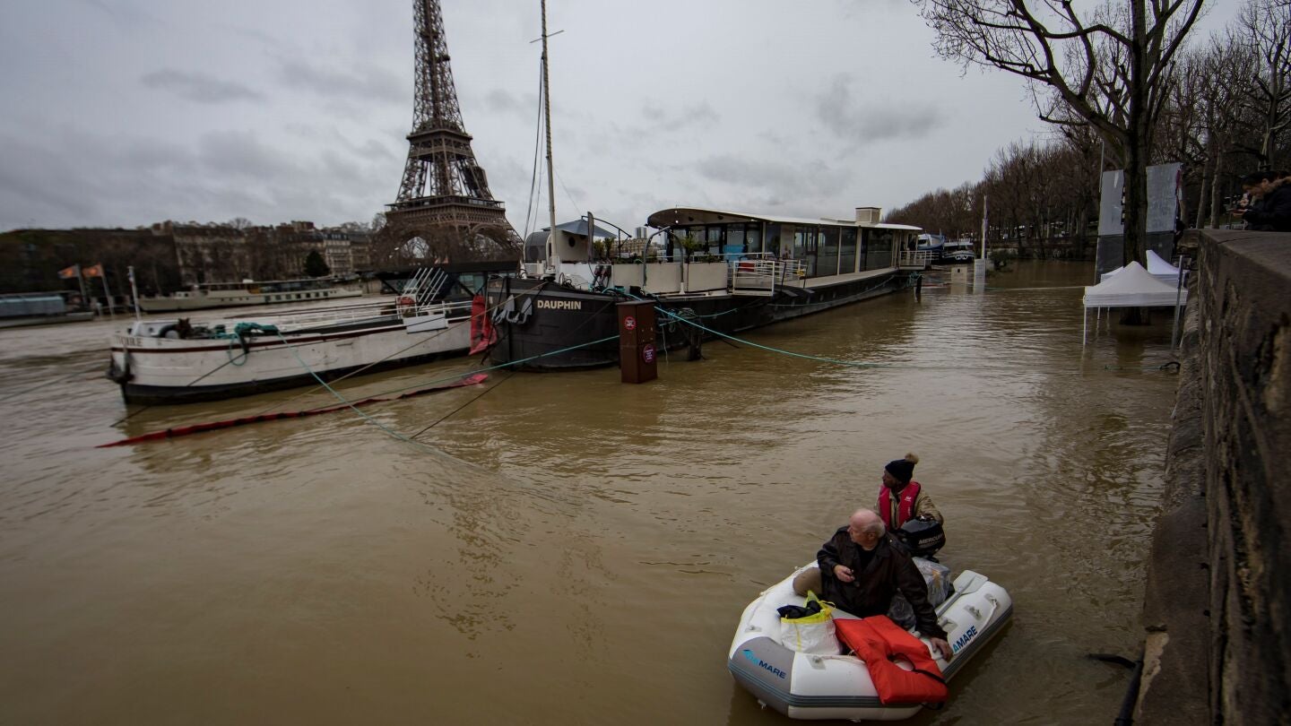  Un hombre transporta a un pasajero en un bote en el desbordado r&iacute;o Sena