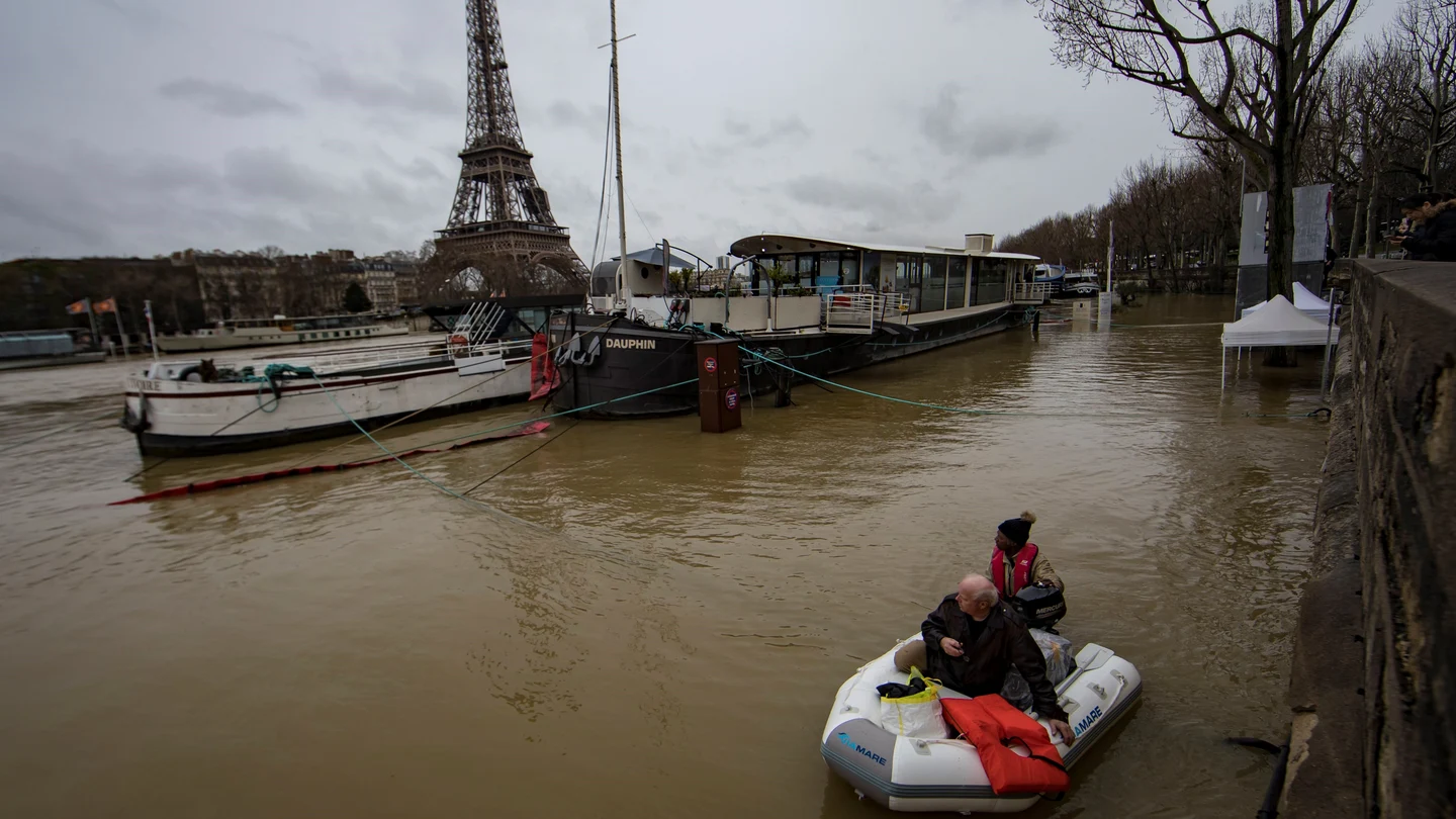 Un hombre transporta a un pasajero en un bote en el desbordado río Sena Un hombre transporta a un pasajero en un bote en el desbordado río Sena