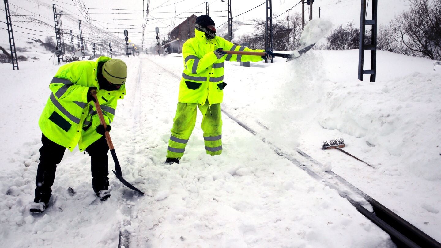 Dos operarios retiran la nieve en la estaci&oacute;n de ferrocarril de Busdongo