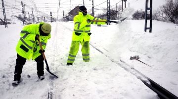 Dos operarios retiran la nieve en la estación de ferrocarril de Busdongo