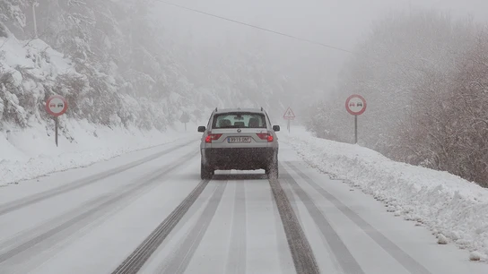 Un vehículo circula por una carretera nevada Un vehículo circula por una carretera nevada