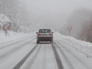 Un vehículo circula por una carretera nevada