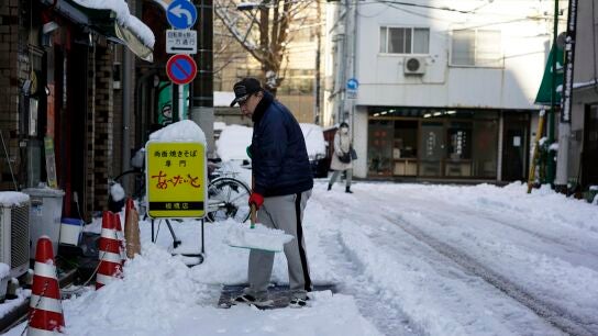 Un hombre despeja la nieve de una acera despu&eacute;s de una nevada en Tokio