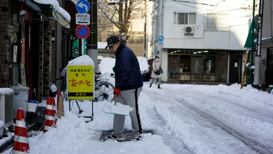 Un hombre despeja la nieve de una acera después de una nevada en Tokio Un hombre despeja la nieve de una acera después de una nevada en Tokio