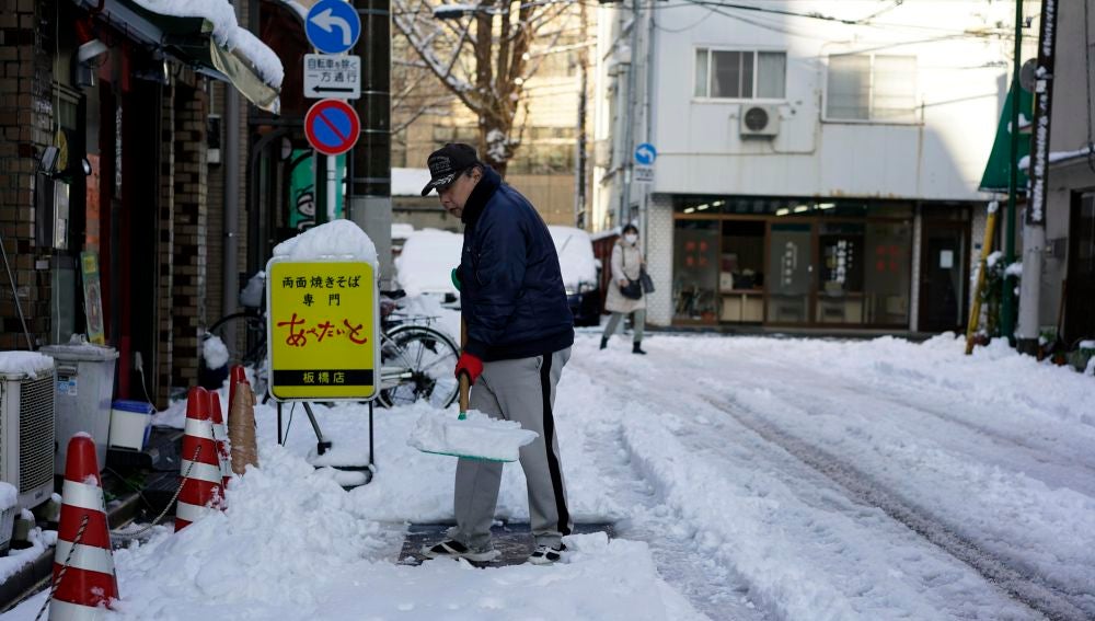 Un hombre despeja la nieve de una acera después de una nevada en Tokio