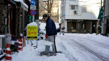 Un hombre despeja la nieve de una acera después de una nevada en Tokio
