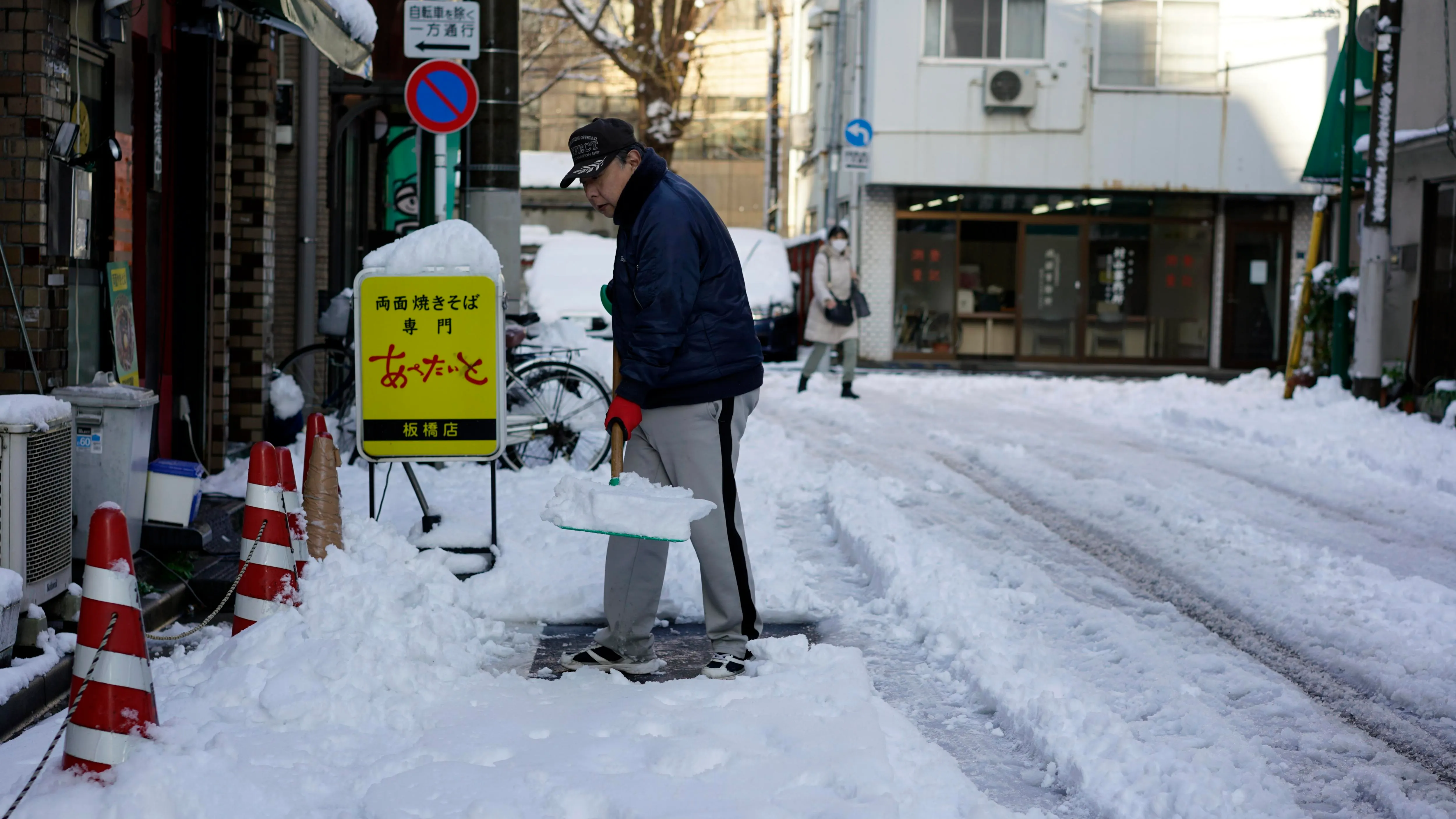 Un hombre despeja la nieve de una acera después de una nevada en Tokio