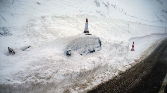 Un veh&iacute;culo permanece cubierto de nieve en el pueblo de Pajares (N-630)