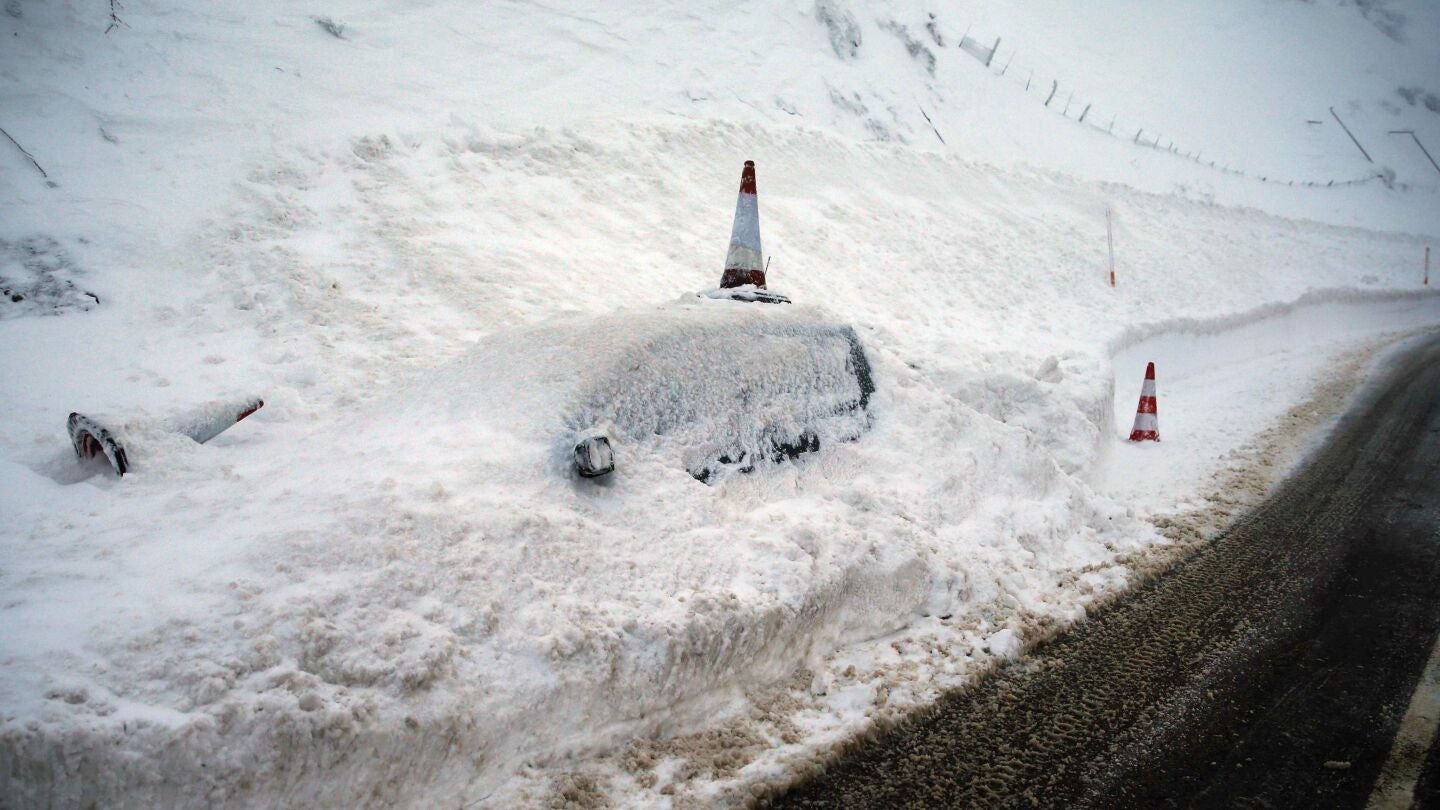 Un veh&iacute;culo permanece cubierto de nieve en el pueblo de Pajares (N-630)