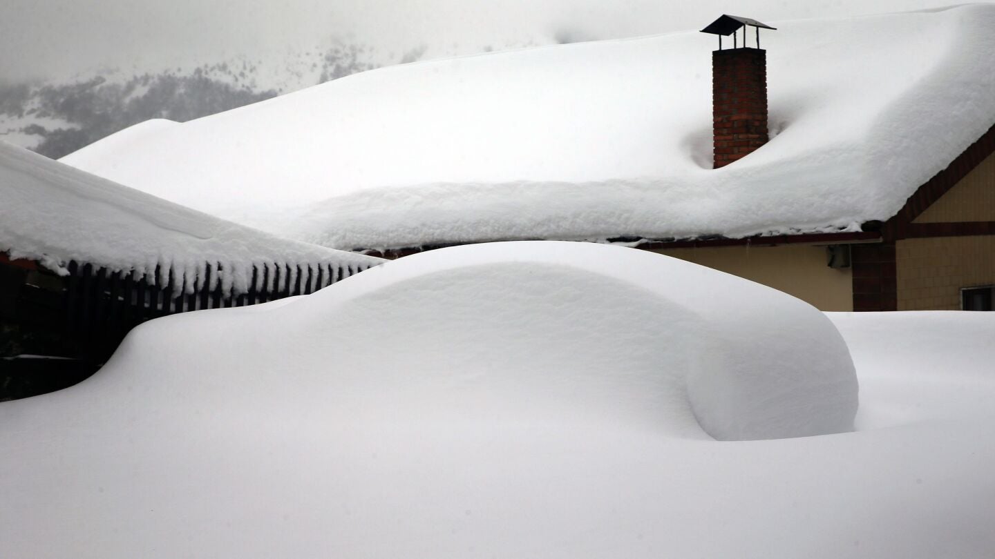 Un veh&iacute;culo cubierto de nieve, en el pueblo asturiano de Pajares