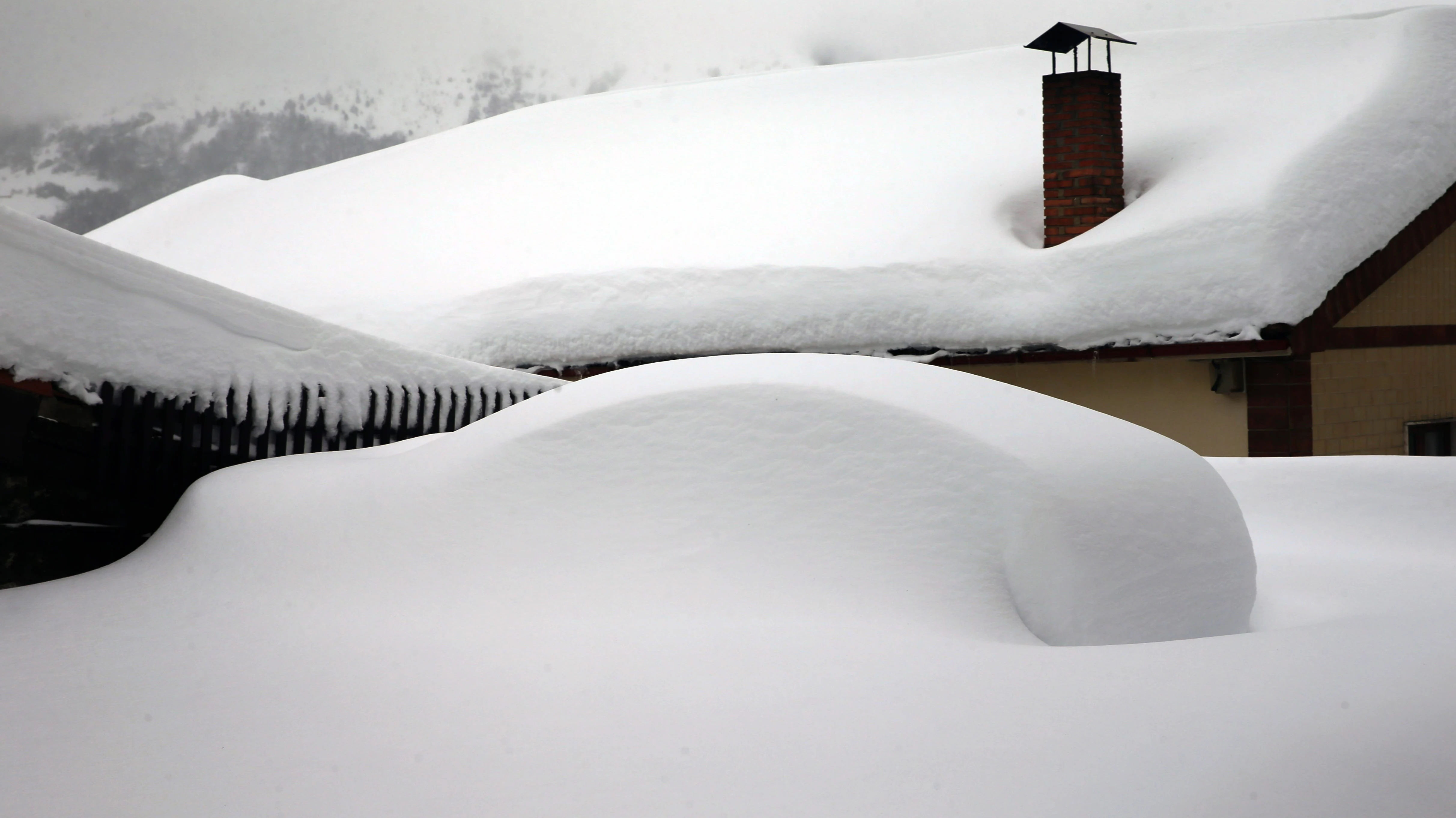 Un vehículo cubierto de nieve, en el pueblo asturiano de Pajares