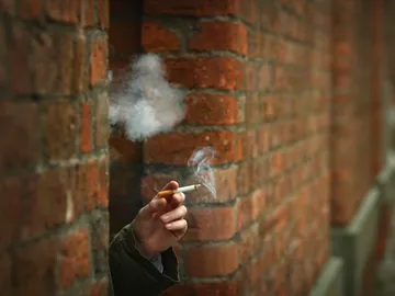 Una mujer fuma en la ventana de su casa Una mujer fuma en la ventana de su casa