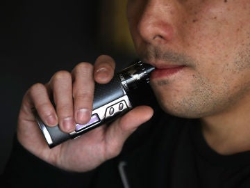 Un hombre fumando de un cigarro electrónico Un hombre fumando de un cigarro electrónico