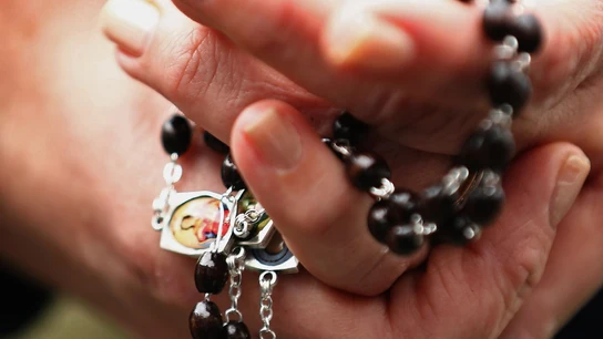 Una mujer con un rosario en las manos Una mujer con un rosario en las manos