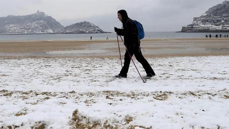 Un hombre camina por la nieve en la Playa de la Concha (San Sebastián)