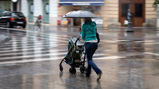 Una mujer con un carrito se protege con un paraguas de la lluvia Una mujer con un carrito se protege con un paraguas de la lluvia