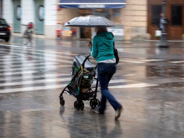 Una mujer con un carrito se protege con un paraguas de la lluvia Una mujer con un carrito se protege con un paraguas de la lluvia