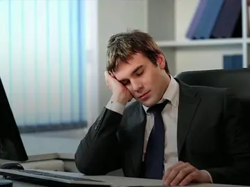 Un empleado está cansado mientras cumple con su jornada laboral Un empleado está cansado mientras cumple con su jornada laboral