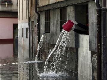 Una persona vierte el agua recogida que ha entrado en las cocinas de un restaurante de Tudela Una persona vierte el agua recogida que ha entrado en las cocinas de un restaurante de Tudela