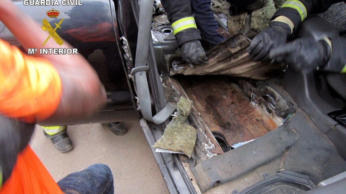 La polic&iacute;a abriendo un doble fondo de un coche para sacar a un menor