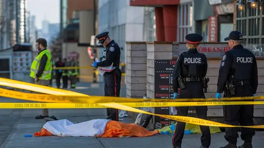 Oficiales de la policía de Toronto vigilan frente al cuerpo de una de las víctimas Oficiales de la policía de Toronto vigilan frente al cuerpo de una de las víctimas