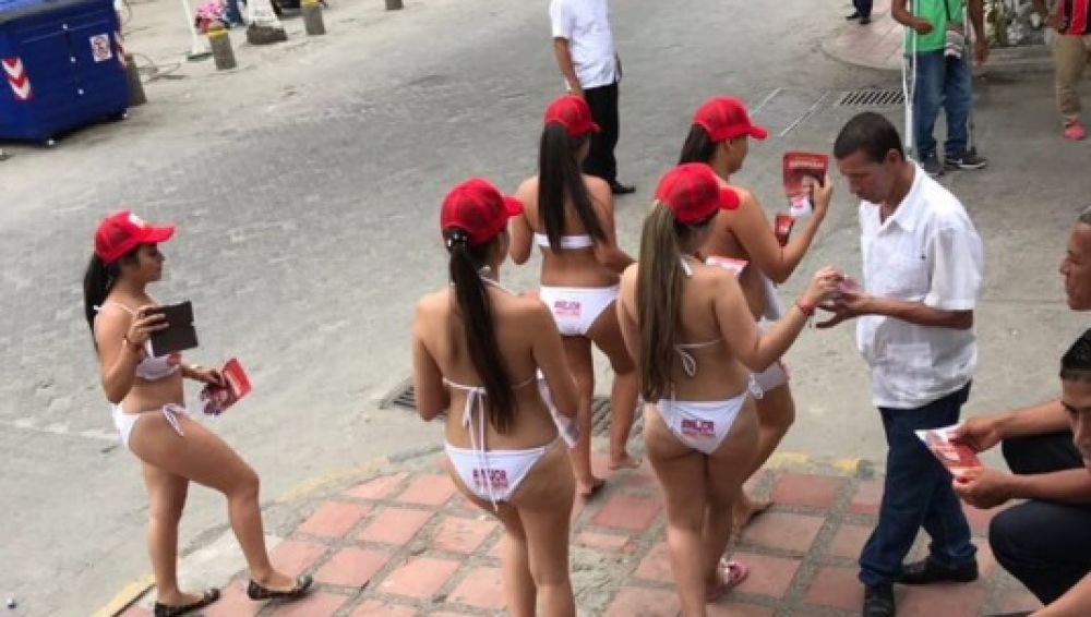 Imagen del momento en el que un grupo de mujeres reparten propaganda en bikini