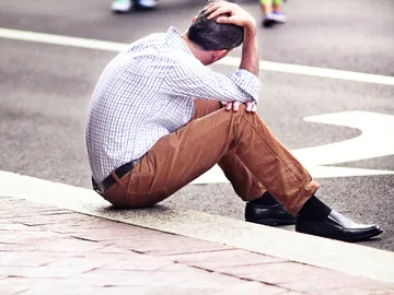 Un hombre sentado en la calle Un hombre sentado en la calle