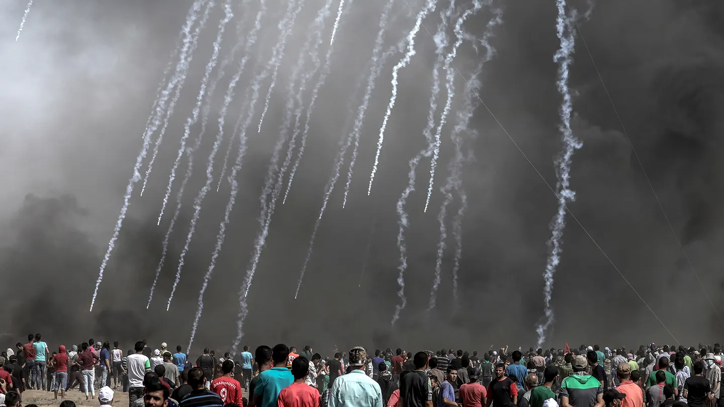 Cientos de palestinos observan las cápsulas de gases lacrimógenos lanzadas por Israel Cientos de palestinos observan las cápsulas de gases lacrimógenos lanzadas por Israel