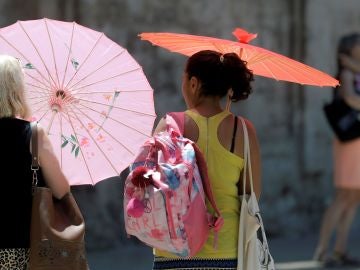Dos mujeres se protegen del calor con unas sombrillas Dos mujeres se protegen del calor con unas sombrillas