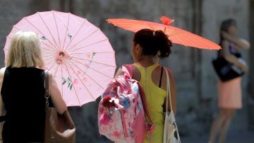 Dos mujeres se protegen del calor con unas sombrillas